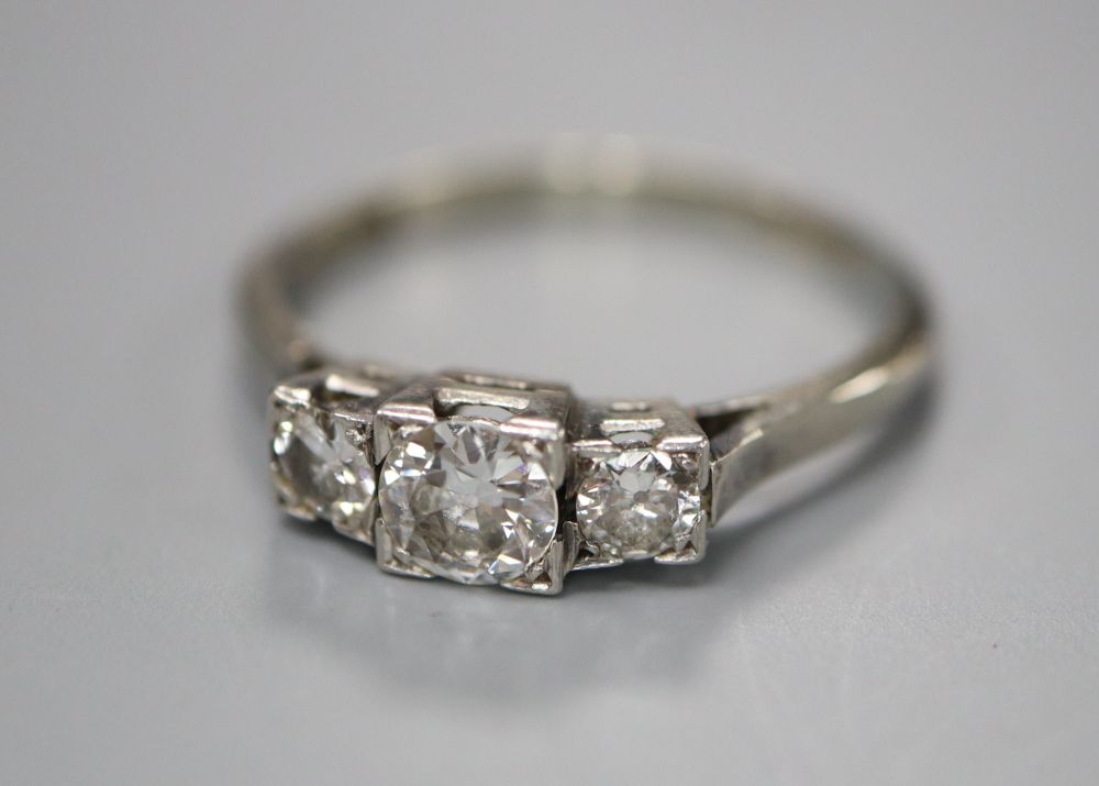 An 18ct and plat, graduated three stone diamond ring, size N/O, gross 3 grams.